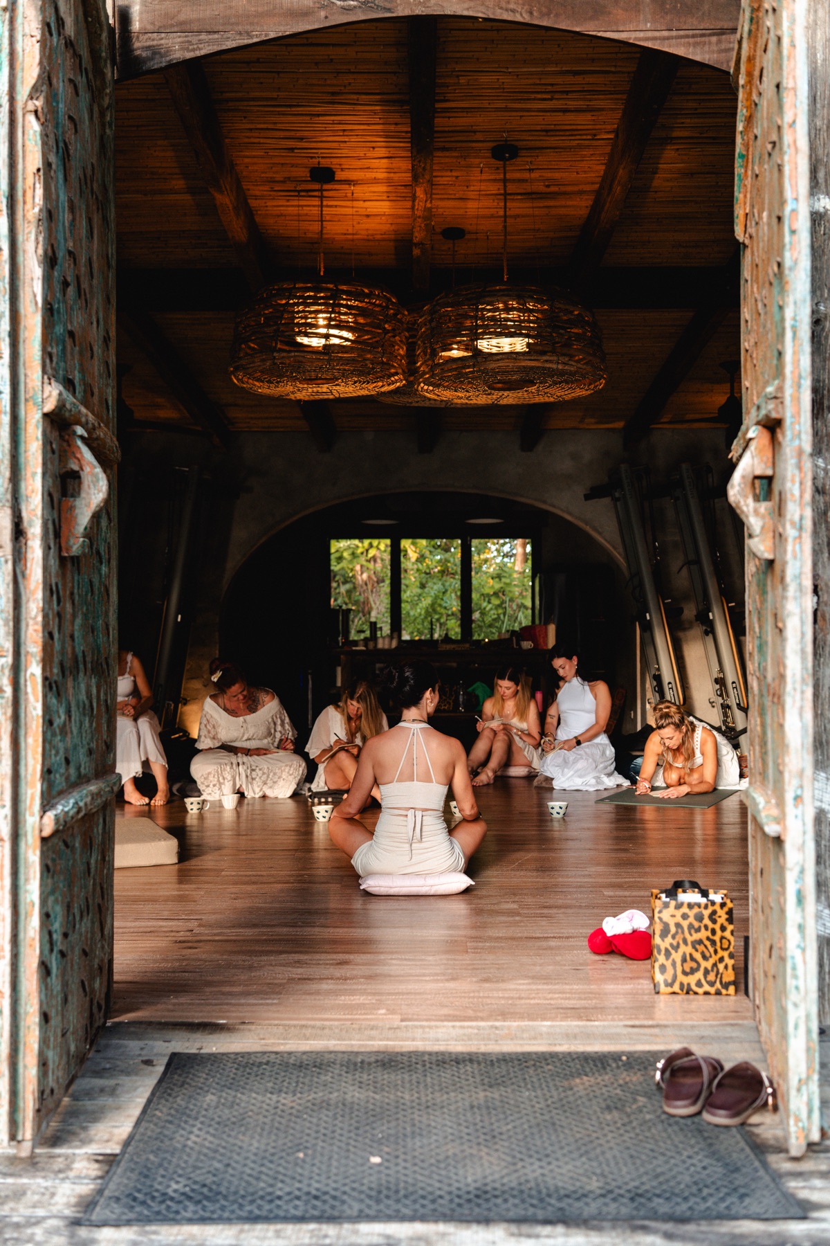 Megsy facilitating a live retreat, women seated together journaling in a warm wooden studio